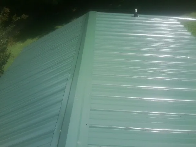 New green metal panels meeting at the ridge of a roof — Flat Roof Repair work by our crew in Washougal
