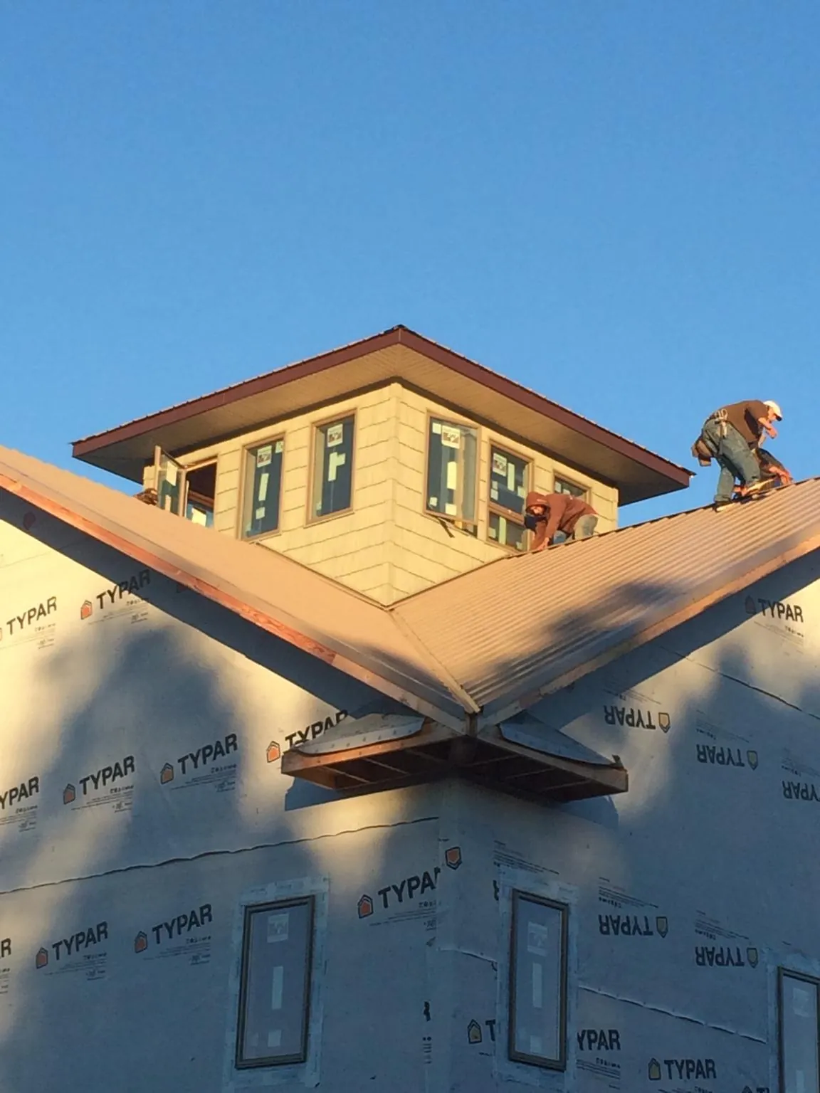 Roofers working around a rooftop cupola on a new metal roof at sunset — Roof Waterproofing in Washougal by Roofing Brothers